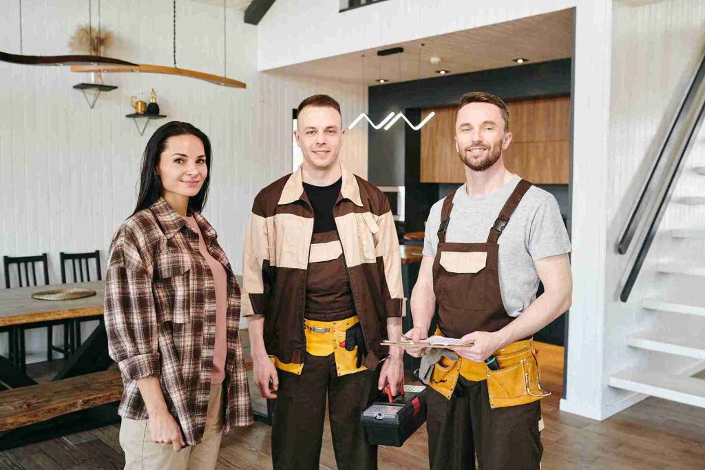 young-woman-and-two-plumbers-standing-in-living-ro-2023-11-27-05-02-13-utc_11zon
